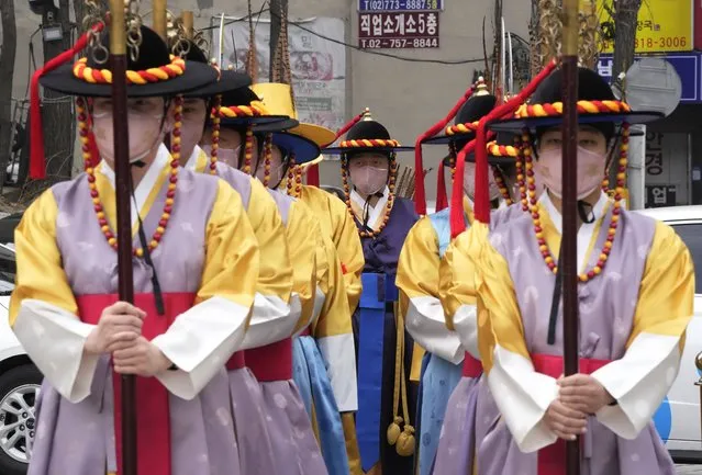 Performers wearing traditional guard uniforms and face masks stand during a reenactment of opening and closing of the gate at the Sungnyemun Gate in Seoul, South Korea, Tuesday, March 15, 2022. South Korea had its deadliest day yet of the pandemic on Tuesday as the country grapples with a record surge in coronavirus infections driven by the fast-moving omicron variant. (Photo by Ahn Young-joon/AP Photo)