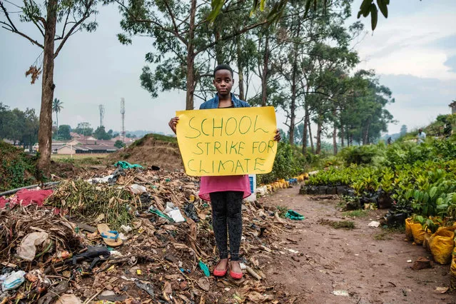 Leah Namugerwa, a 15 year-old climate activist, holds a placard in Kampala on September 4, 2019. Her activism includes striking around the city with a placard in order to raise awareness about climate change and the environment. She also misses out on school every Friday as a protest and has full support from her dad, Lukwago Cephas, who is also her manager. (Photo by Sumy Sadurni/AFP Photo)