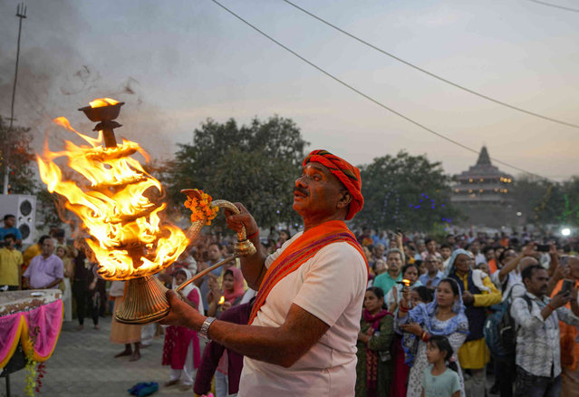 A Hindu priest rotates traditional lamps in circular movement as he performs evening prayers at Sangam, the confluence of the Rivers Ganges, Yamuna and the mythical Saraswati, on the occasion of Ganga Dussehra festival in Prayagraj, Uttar Pradesh state, India, Sunday, June 16, 2024. Hindus across the country celebrate Ganga Dussehra by worshiping the River Ganges, which is considered the most sacred and the holiest river for Hindus. (Photo by Rajesh Kumar Singh/AP Photo)