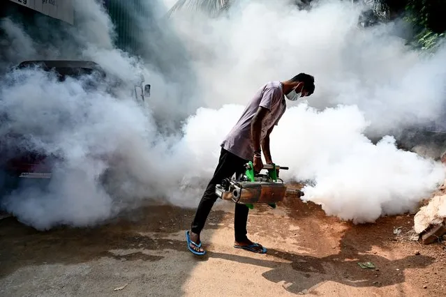 A front-line worker fumigates a neighbourhood to ward off mosquitoes in Colombo on February 25, 2022. (Photo by Ishara S. Kodikara/AFP Photo)