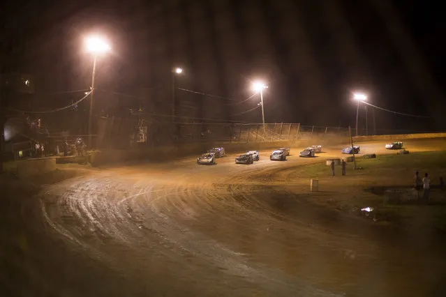 In this July 17, 2015 photo, drivers steer their cars around the D-shaped track under the night lights during dirt track racing at the Ponderosa Speedway in Junction City, Ky. The Speedway, in operation since 1972, is among a handful of dirt racetracks sprinkled across Kentucky where weekend drivers, their crews and families can test their mechanical and driving skills. (Photo by David Stephenson/AP Photo)