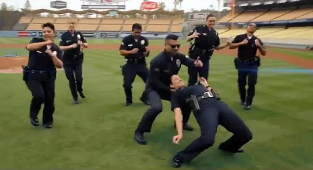 In this undated frame from video provided by the Los Angeles Police Department, LAPD officers dance on the field at Dodger Stadium in Los Angeles. In a now-viral sensation, police officers across the U.S. are dancing an updated version of the running man to a catchy 1990s hip hop song, “My Boo” by Ghost Town DJ's, in videos that have included professional sports mascots, cheerleading squads and at least one explosion. The videos started with the New York Police Department and are getting more elaborate and popular, with even some police chiefs joining in. (Photo by Los Angeles Police Department via AP Photo)