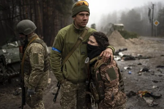 Ukrainian army soldiers, Igor, 23, embraces his wife Dasha, 22, after conducting a military sweep to search for possible remnants of Russian troops after their withdrawal from villages on the outskirts of Kyiv, Ukraine, Friday, April 1, 2022. (Photo by Rodrigo Abd/AP Photo)