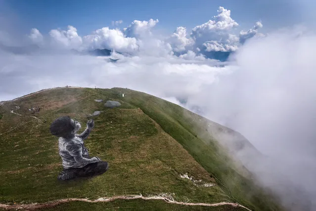 An areal photograph taken on August 24, 2021 on the top of the Moleson mountain, in the Swiss Prealps, overlooking the region of Gruyeres, shows a giant land art fresco by French artist Guillaume Legros, known as Saype, entitled: “A new breath” representing a boy blowing clouds. The artwork, covering approximately 1500 square meters, was produced with biodegradable paint made from chalk charcoal, water and milk protein. (Photo by Fabrice Coffrini/AFP Photo)