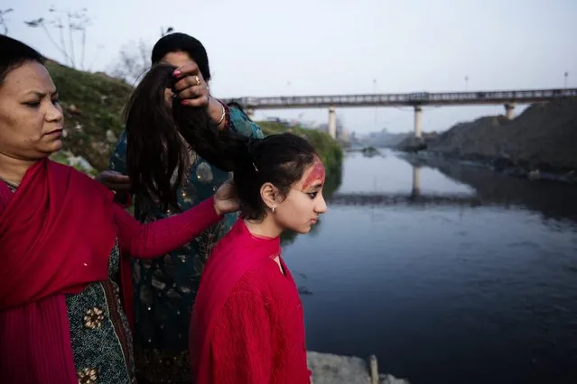 Purna Shova (L) unties the hair of her daughter Kumari Samita Bajracharya (R) after completing 12 days of “Gufa” ritual, at Bagmati river in Patan, Nepal, 07 March 2014. This ritual represents the end of Samita as a Kumari. (Photo by Narendra Shrestha/EPA)