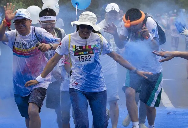 Participants are sprayed by color powder as they run through a “color station” during the five-kilometer color run event in Beijing, China Saturday, June 21, 2014. (Photo by Andy Wong/AP Photo)