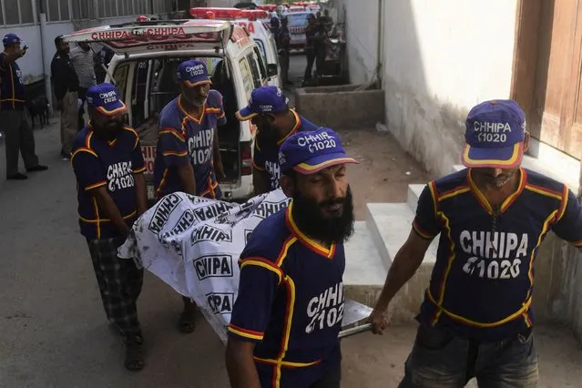 Volunteers shift a body of a suicide blast that killed four people, including three Chinese nationals, in an attack on a vehicle carrying staff from the Confucious Institute affiliated with the Karachi University, outside a hospital in Karachi on April 26, 2022. (Photo by Asif Hassan/AFP Photo)