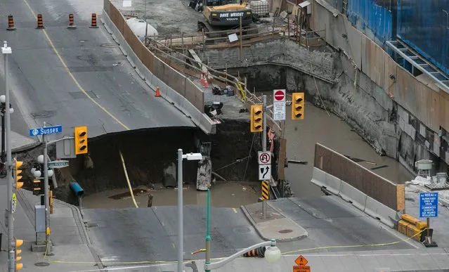 A large portion of Rideau Street in downtown Ottawa, Ontario is seen caved in, causing a massive sinkhole that knocked out power to the majority of the downtown area on June 8, 2016. The massive sinkhole formed next to a shopping mall in downtown Ottawa, caused a gas leak and forced the evacuation of all nearby businesses. (Photo by Chris Roussakis/AFP Photo)