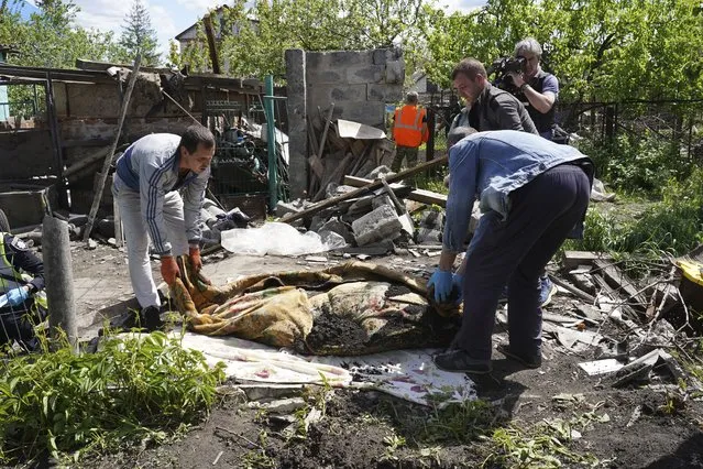 Police and volunteers exhume the body of a civilian killed by Russian shelling in the village of Malaya Rohan, on the outskirts of Kharkiv, Monday, May 16, 2022. (Photo by Andrii Marienko/AP Photo)