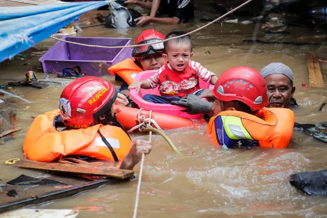 Indonesian rescuers evacuate a boy from a flooded area in Jakarta, Indonesia, 02 January 2020. Overnight heavy rains triggered w​idespread flooding in Jakarta and surrounding areas, killing at least 21. (Photo by Mast Irham/EPA/EFE)