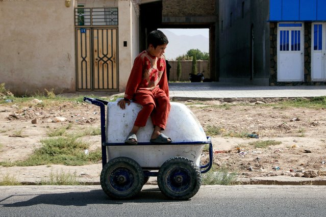 An Afghan boy sits on his cart of ice-creams as he waits for customers along street in Herat on July 29, 2024. (Photo by Mohsen Karimi/AFP Photo)