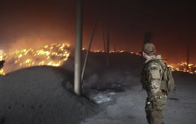 An Ukrainian serviceman looks at a sunflower seeds storage on fire after shelling on a farm close to the front line near the city of Bakhmut, Donetsk region, Ukraine, 31 May 2022. Russian troops entered Ukraine on 24 February resulting in fighting and destruction in the country and triggering a series of severe economic sanctions on Russia by Western countries. (Photo by EPA/EFE/Stringer)