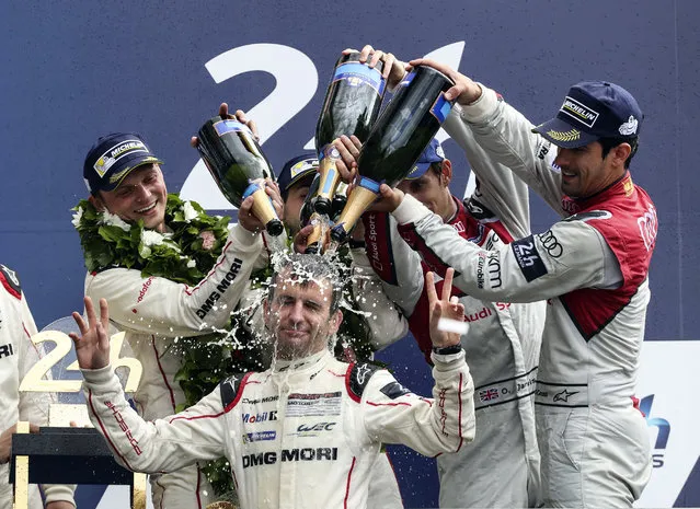 The Porsche 919 Hybrid No2 of the Porsche Team driven by Neel Jani of Switzerland, Romain Dumas of France, Marc Lieb of Germany and Coach driver Jeromy Moore celebrate with champagne, after winning the 84th 24-hour Le Mans endurance race, in Le Mans, western France, Sunday, June 19, 2016. (Photo by Kamil Zihnioglu/AP Photo)