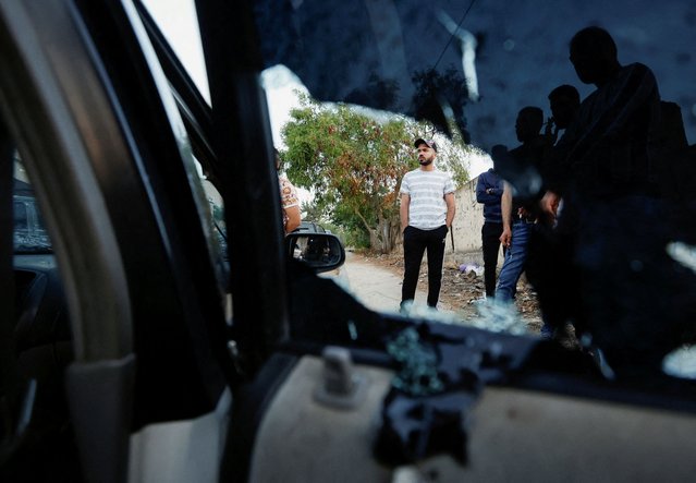 People stand next to a damaged vehicle following an Israeli raid in Jenin, in the Israeli-occupied West Bank on June 17, 2022. (Photo by Mohamad Torokman/Reuters)