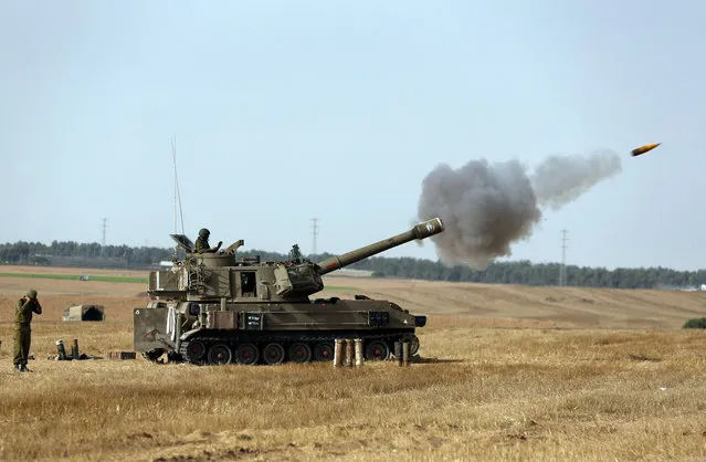 Israeli soldiers on a mobile artillery unit fire a shell towards Gaza at a position on the Israel-Gaza border, Saturday, July 12, 2014. Israeli airstrikes overnight targeting Hamas in Gaza hit a mosque its military says concealed the militant group's weapons, in an offensive that showed no signs of slowing down. Israel launched its campaign five days ago to stop relentless rocket fire on its citizens. (Photo by Lefteris Pitarakis/AP Photo)
