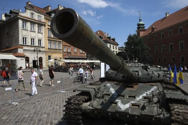 People visit an open-air exhibition of damaged and burnt-out Russian tanks and armored vehicles at the Castle Square, in Warsaw, Poland, Monday, June 27, 2022. The vehicles were captured by Ukrainian military forces during the war in the Ukraine. Ukrainian authorities announced that there are plans for similar exhibits in other European capitals such as Berlin, Paris, Madrid and Lisbon. (Photo by Michal Dyjuk/AP Photo)