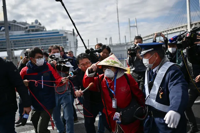 A passenger (C) leaves on foot after dismembarking the Diamond Princess cruise ship in quarantine due to fears of the new COVID-19 coronavirus, at the Daikoku Pier Cruise Terminal in Yokohama on February 19, 2020. Several hundred passengers who have endured a torrid 14-day quarantine aboard a coronavirus-riddled cruise ship in Japan are set to disembark February 19 – if they have tested negative. (Photo by Charly Triballeau/AFP Photo)
