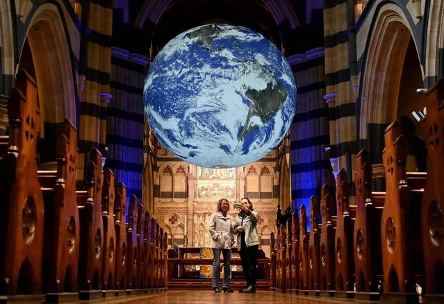 People look at a giant globe of the world measuring seven metres in diameter, – an artwork titled “Gaia” by artist Luke Jerram – which is suspended and rotates from the ceiling of St Paul's Cathedral in Melbourne on May 11, 2022. (Photo by William West/AFP Photo)