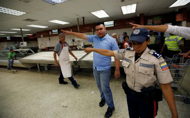 Workers and police officers point as people line up to buy food and other staple goods inside a supermarket in Caracas, Venezuela June 30, 2016. (Photo by Mariana Bazo/Reuters)