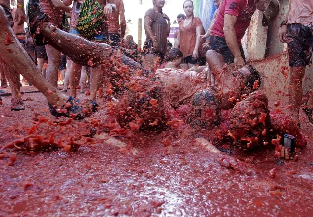 Revelers play in tomato pulp after the annual “Tomatina” (tomato fight) in Bunol, near Valencia, Spain, August 26, 2015. Tens of thousands of festival-goers hurled 170 tonnes of over-ripe tomatoes at each other on Wednesday to celebrate the 70th anniversary of the massive food fight in the small village of Bunol in eastern Spain. (Photo by Heino Kalis/Reuters)