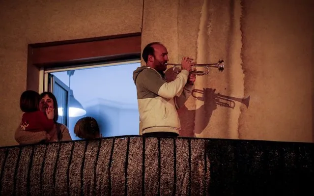 A resident plays a trumpet in his balcony to thank paramedics' work at 20.00 hour like every other day in a residential building in San Sebastian, Basque Country, northern Spain, 19 March 2020 (issued on 20 March 2020). Spain faces the sixth day of national lockdown on 20 March in an effort to slow down the spread of the pandemic COVID-19 disease caused by the SARS-CoV-2 coronavirus. (Photo by Javier Etxezarreta/EPA/EFE)