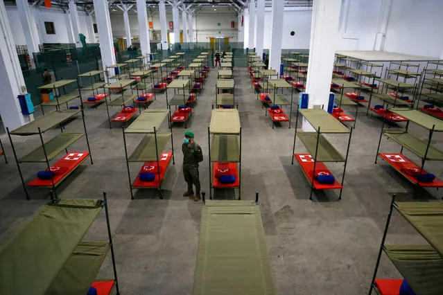 A Spanish soldier stands next to beds set up at a temporary hospital for vulnerable people at the Fira Barcelona Montjuic centre in Barcelona on March 25, 2020, during the new coronavirus epidemic. Spain's coronavirus death toll overtook that of China, rising to 3,434 after 738 people died over the past 24 hours, the government said. The spiralling number of deaths came as Spain entered the 11th day of an unprecedented lockdown to try and rein in the COVID-19 epidemic that has now infected 47,610 people, the health ministry said. (Photo by Pau Barrena/AFP Photo)