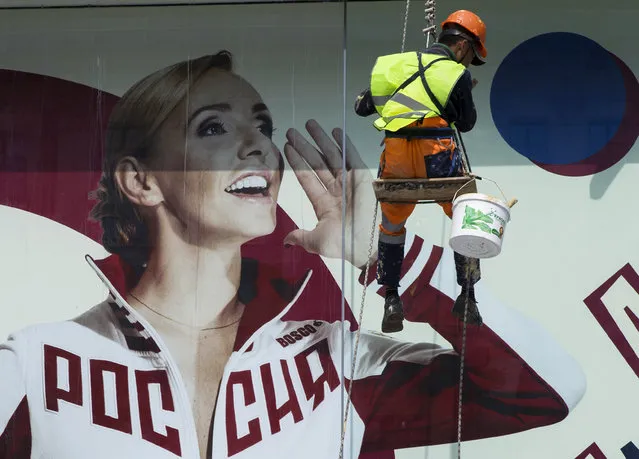 A municipal worker cleans a shop window of a display with a portrait of Russia's Olympic champion Tatyana Navka dressed in a Russian Olympic National team uniform in Moscow, Russia, Tuesday, July 19, 2016. The executive board of the International Olympic Committee has a teleconference on Tuesday, July 19, 2016 to go over options in the wake of a report that uncovered a state-run doping scheme in Russia. After receiving the evidence from the report it commissioned, the World Anti-Doping Agency called for the IOC to consider a ban of Russia's entire Olympic team. (Photo by Pavel Golovkin/AP Photo)
