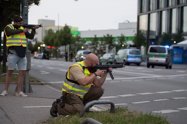 Police officers point their weapons outside the Olympia mall in Munich, southern Germany, Friday, July 22, 2016 after several people have been killed in a shooting. (Photo by Sebastian Widmann/AP Photo)