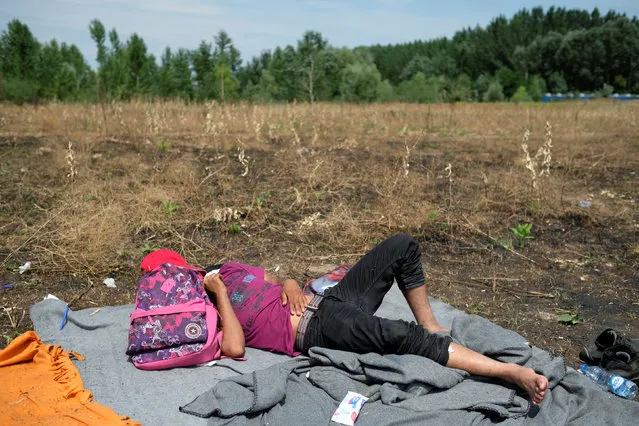 A migrant from Afghanistan rests on a field near the Serbian-Hungarian border fence during a hunger strike near the village of Horgos, Serbia July 25, 2016. (Photo by Marko Djurica/Reuters)