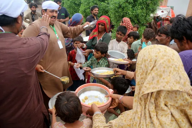 People affected by monsoon rains receive free food  in Hyderabad, Pakistan, 25 August 2022. (Photo by Nadeem Khawar/EPA/EFE)