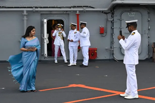 A Naval officer takes a picture of a woman on the deck of the Indian indigenous aircraft carrier INS Vikrant during its commissioning at Cochin Shipyard in Kochi on September 2, 2022. India debuted its first locally made aircraft carrier on September 2, a milestone in government efforts to reduce its dependence on foreign arms and counter China's growing military assertiveness in the region. (Photo by Arun Sankar/AFP Photo)