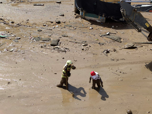 In this photo provided by the Iranian Red Crescent Society, members of a rescue team work at the site of a flash flood in the northwestern part of Tehran, Iran, Thursday, July 28, 2022. (Photo by Iranian Red Crescent Society via AP Photo)