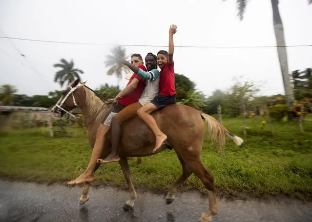 People on a horse wave in the streets of Coloma, a town through which Hurricane Ian is expected to enter, in Pinar del Rio province, Cuba, 26 September 2022. (Photo by Yander Zamora/EPA/EFE)