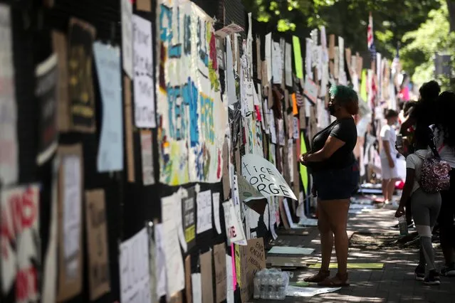 People gather to view protest signs now affixed to the fence around Lafayette Square at the scene where protesters clashed with police in the aftermath of the death in Minneapolis police custody of George Floyd, near the White House in Washington, U.S. June 8, 2020. (Photo by Jonathan Ernst/Reuters)