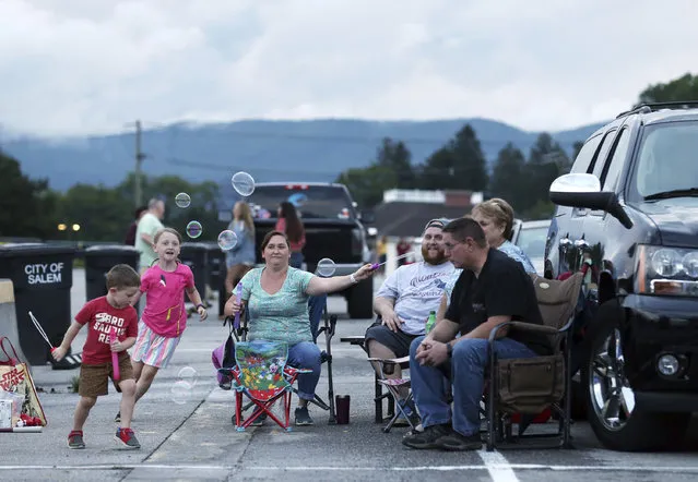 Alice Carr, 7, and her bother Bruce Carr, 3, chase bubbles being made by their mom, Olivia Carr, with their dad, Brandon Carr, and grandparents Rhonda and Eric Carr during a drive-in concert with Crawford & Power in the Salem Civic Center parking lot Thursday, June 18, 2020, in Salem, Va., amid the coronavirus pandemic. (Photo by Heather Rousseau/The Roanoke Times via AP Photo)