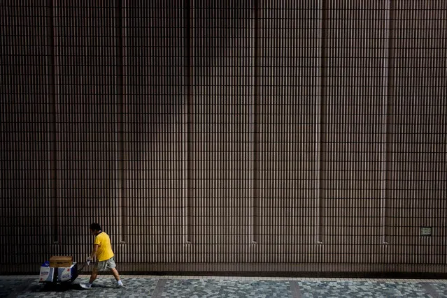 A man (bottom L) walks past the Hong Kong Cultural Centre as he makes a delivery in the territory's Tsim Sha Tsui district on August 23, 2016. (Photo by Isaac Lawrence/AFP Photo)