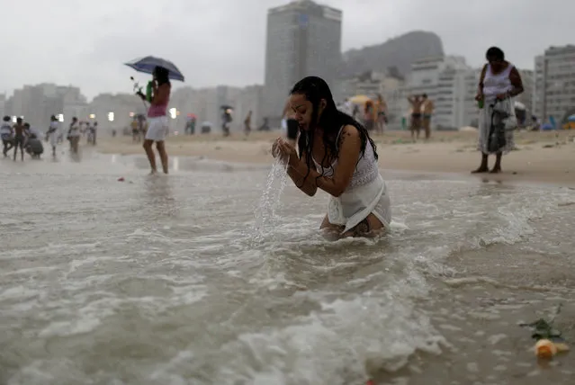 A follower of the Afro-Brazilian religion Umbanda pays tribute for Iemanja, goddess of the sea, in Copacabana Beach in Rio de Janeiro, Brazil December 29, 2017. Hundreds of practitioners of Brazil's Afro-Brazilian Candomble and Umbanda faiths have gathered at Rio de Janeiro's Copacabana beach to honor Yemanja. Worshippers were mostly dressed in white as they launched their offerings to Iemanja: small boats with flowers and bowls with candles and fruits. (Photo by Ricardo Moraes/Reuters)