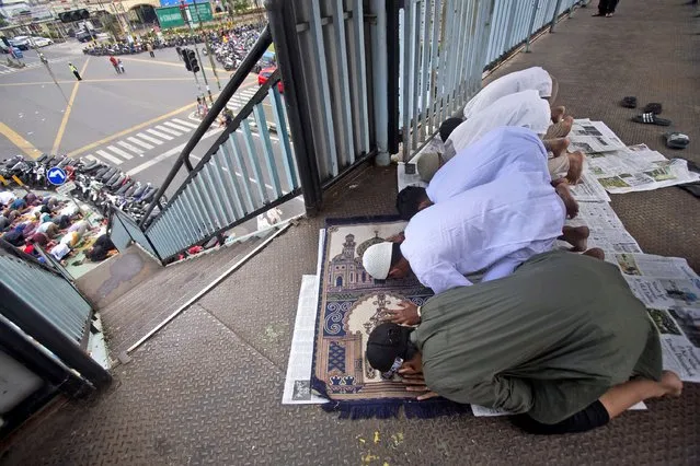 Muslim youths pray on a pedestrian bridge outside a crowded mosque during an Eid al-Adha prayer in Medan, North Sumatra, Indonesia, Friday, July 31, 2020. Eid al-Adha, or “Feast of the Sacrifice”, is a holiday which honors the prophet Ibrahim, or Abraham, as he is known in the Bible, for his willingness to sacrifice his son on the order of God who was testing his faith. (Photo by Binsar Bakkara/AP Photo)