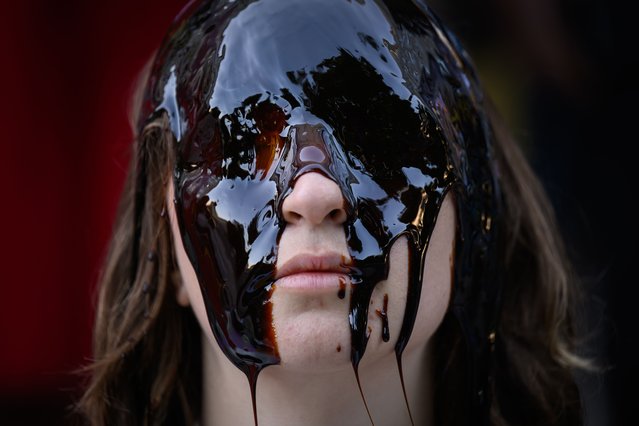 An activist from Fossil Free London sits with an oil-like substance on her face during a demonstration outside the offices of the Shell energy company on May 20, 2025 in London, England. Extinction Rebellion activists gathered outside Shell's headquarters in London as the oil giant held its Annual General Meeting at Heathrow Airport, where demonstrations are restricted under a court injunction. The protest comes amid growing criticism of Shell's recent sale of its onshore oil assets in Nigeria to a new entity, Renaissance, a deal partially funded by a $1.5 billion loan from Shell itself. Campaigners accuse the company of attempting to sidestep legal responsibility for decades of oil spills and environmental degradation in the Niger Delta, while still profiting from the region. (Photo by Leon Neal/Getty Images)