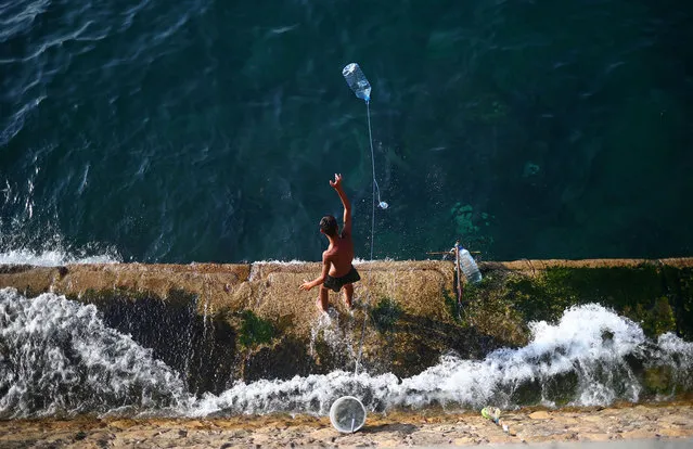 A boy is seen fishing at Beirut's seaside Corniche, Lebanon on August 13, 2020. (Photo by Hannah McKay/Reuters)