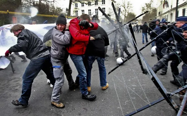 Steel workers in clash with riot police using pepper spray, during a protest outside the Prime Minister's office in Brussels, January 25, 2013. The world's leading steel and mining company ArcelorMittal announced that it will close a coke plant and six production lines in Belgium, in a move that threatens 1,300 jobs. (Photo by Yves Logghe/Associated Press)