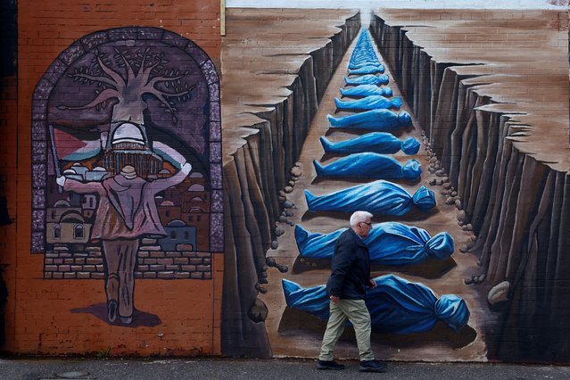 A man walks past pro-Palestinian murals on the International Wall in support of Gaza, amid the ongoing conflict between Israel and the Palestinian Islamist group Hamas, in Belfast, Northern Ireland, on March 29, 2024. (Photo by Clodagh Kilcoyne/Reuters)
