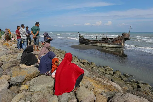 Villagers look at a wooden boat used by Rohingya people in Pidie, Aceh province on December 27, 2022. Rohingya refugees received emergency medical treatment after a boat carrying nearly 200 people came ashore in Indonesia on December 26, authorities said, in the fourth such landing in the country in recent months. (Photo by Amanda Jufrian/AFP Photo)