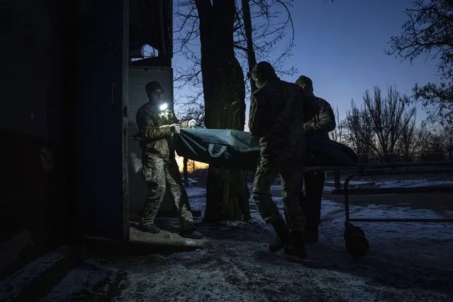 Ukrainian military medics carry a body of their killed comrade into a morgue in Donetsk region, Ukraine, Monday, January 9, 2023. (Photo by Evgeniy Maloletka/AP Photo)