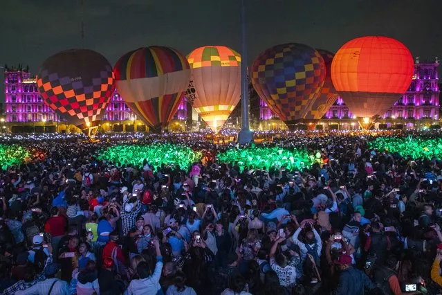 Thousands of people attend the “Magic Night” event in Mexico City, Mexico, 22 October 2022. The Zocalo of the Mexican capital was the setting for the launch of the Leon International Balloon Festival; attendees enjoyed the inflation and deployment of eight hot air balloons, as a sample of the show scheduled for November in the city of León, state of Guanajuato. (Photo by Isaac Esquivel/EPA/EFE)