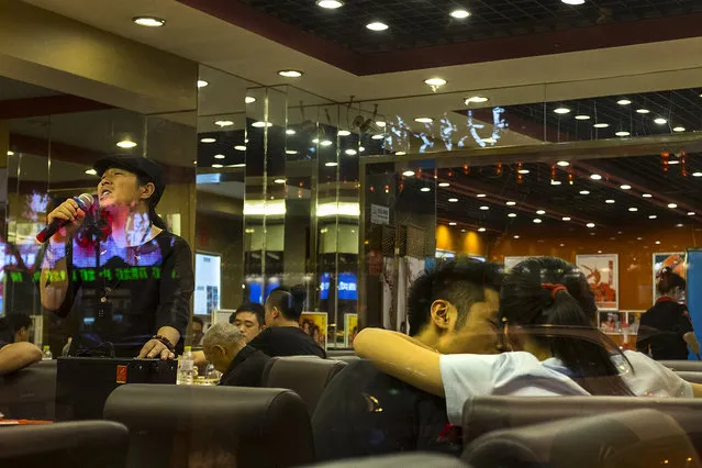 A couple enjoys one another's company as a karaoke crooner sings inside a restaurant on Beijing's famous “Ghost Street” on May 26, 2016. The city is in a rapid state of development as it tries to remain as economically vital as Shanghai and Guangzhou. (Photo by Michael Robinson Chavez/The Washington Post)
