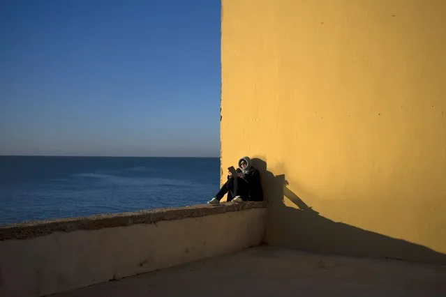 A woman reads by the sea while the first rays of sunlight fall on the city of Cadiz, Spain, Friday, January 27, 2023. (Photo by Emilio Morenatti/AP Photo)