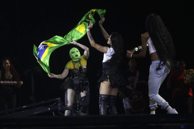 American singer-songwriter and actress Madonna, left, wearing a mask, and Brazilian singer Pabllo Vittar wave a national flag during a rehearsal of The Celebration Tour, in Rio de Janeiro, Brazil, Friday, May 3, 2024. Madonna will conclude her tour on Saturday with a free concert at Copacabana Beach. (Photo by Bruna Prado/AP Photo)
