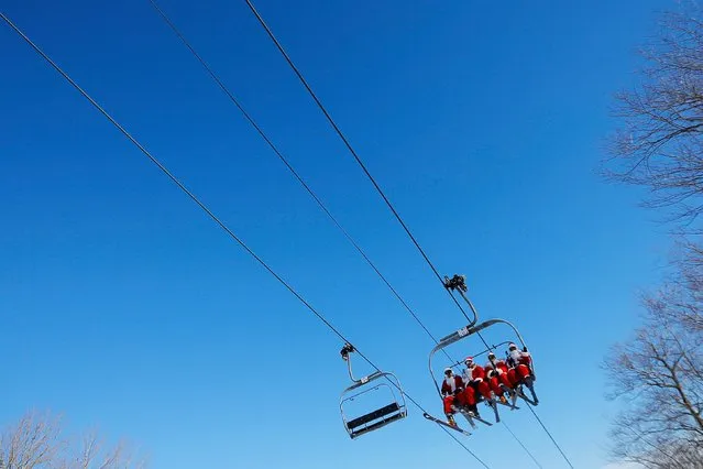 Skiers and snowboarders dressed as Santa Claus ride a chair lift to participate in a charity run down a slope at Sunday River Ski Resort in Newry, Maine December 7, 2014. (Photo by Brian Snyder/Reuters)