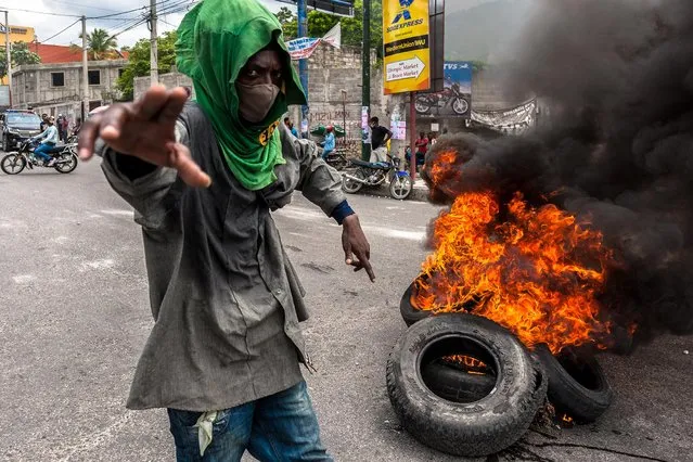 A protester is seen near a burning tires during a protest as police officers and members of Haitian civil society march through the streets of the capital of Haiti in Port-au-Prince on September 14, 2020. Haitian police officers and their supporters, many of them armed and wearing masks, sparked panic in the capital Port-au-Prince on September 14, setting cars on fire, arson and destruction of public property as they voiced their anger at the ruling party. The cops have demanded higher salaries and the release of a colleague – a member of the narcotics squad has been held since early May on suspicion of murder. (Photo by Sabin Johnson/Anadolu Agency via Getty Images)